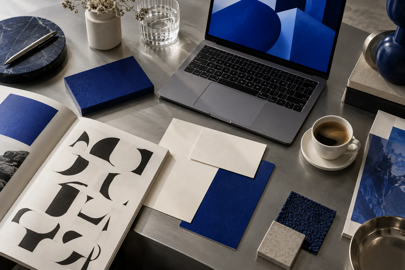 Bureau de studio créatif, carnets bleu cobalt, ordinateur et échantillons de papier